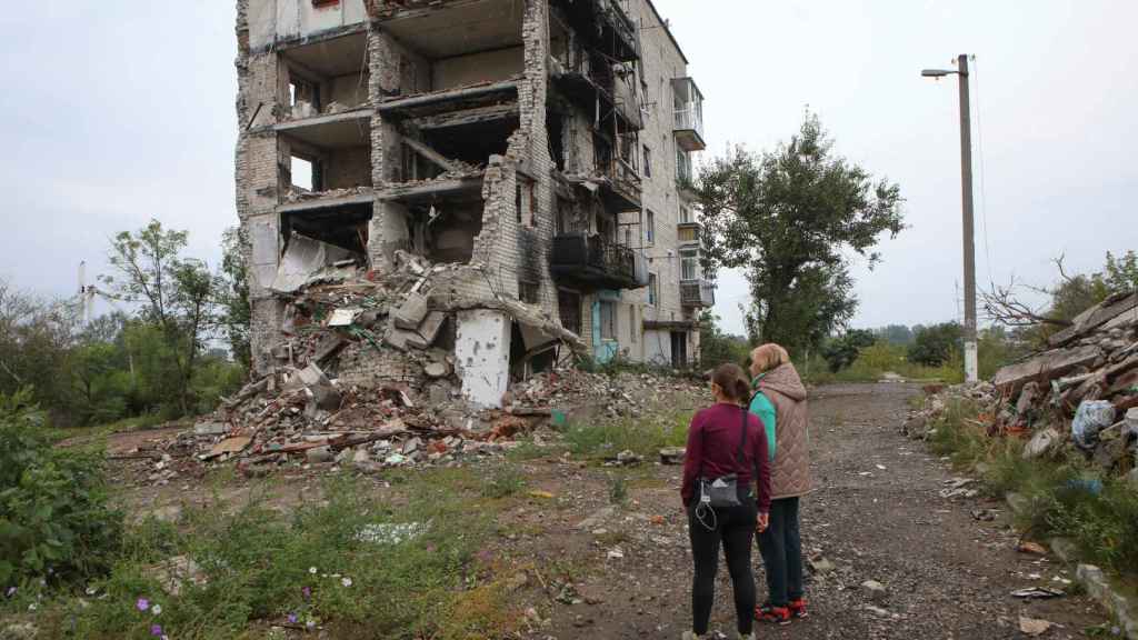 Des femmes se tiennent près d'un bâtiment résidentiel détruit par une attaque militaire dans la ville d'Izium.