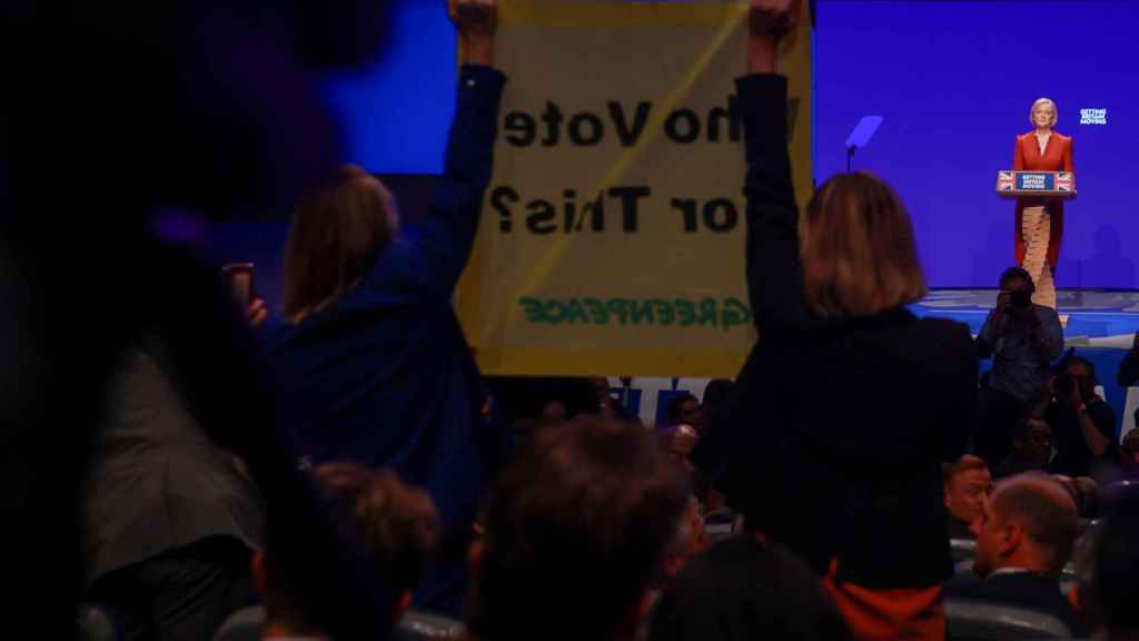 Des activistes de Greenpeace se tiennent devant Truss avec une bannière : 