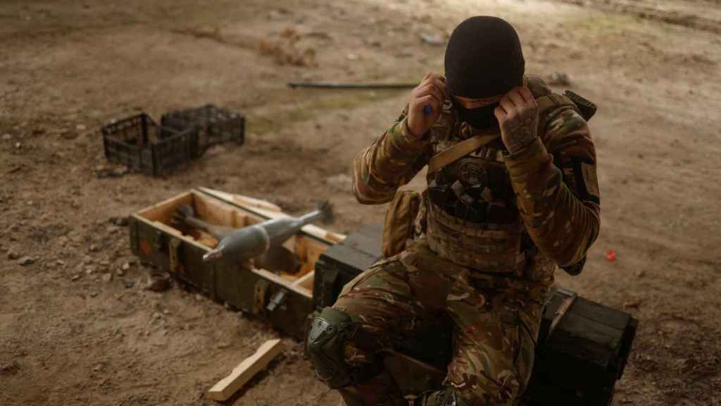 Un soldat ukrainien est assis sur des obus de mortier russes capturés dans le village de Blahodatne, dans la région de Kherson.