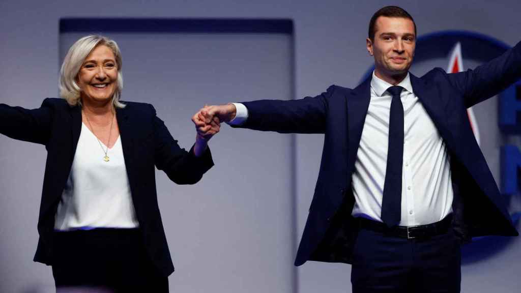 Jordan Bardella, nouveau président du parti d'extrême droite Rassemblement national, tient la main de son prédécesseur, Marine Le Pen.