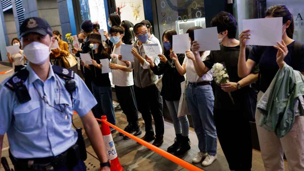 Une file de jeunes gens se couvrent le visage de papier blanc en signe de protestation contre la présence des agents chinois.