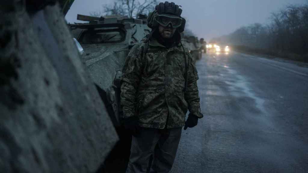 Un membre des services ukrainiens à côté d'un véhicule de transport blindé à Kherson.