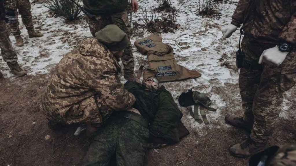 Des soldats du Groupe Wagner à côté d'un soldat ukrainien exécuté.